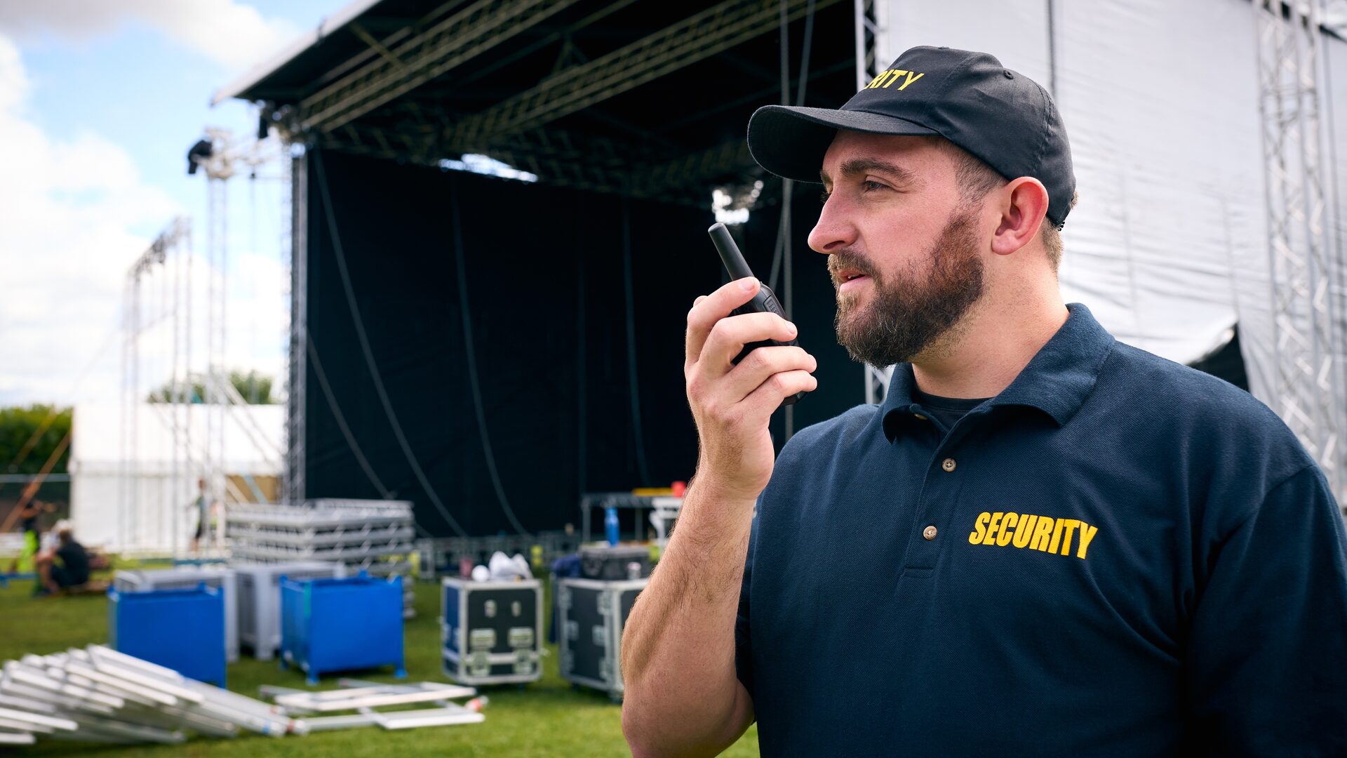 Event security professional using a two-way radio at a festival setup